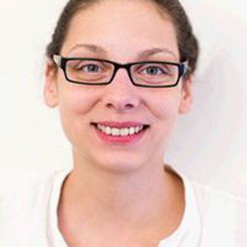 Personne portant des lunettes souriant face à la caméra.