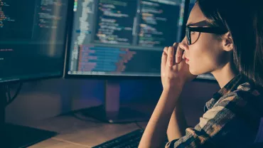 Une personne travaille sur des codes informatiques à l'écran.