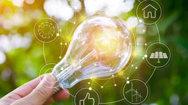 Ampoule lumineuse avec icônes d'énergie renouvelable en arrière-plan flou.