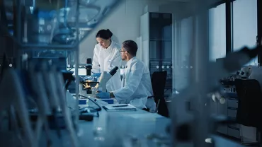 Scientifiques en laboratoire examinant un échantillon sous microscope.