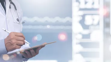 Médecin en blouse blanche écrivant sur une tablette.