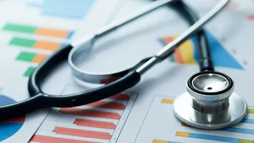 Stéthoscope posé sur des graphiques colorés représentant des données médicales.