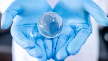 Mains gantées tenant un globe transparent.