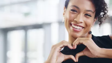 Personne souriante formant un cœur avec ses mains.
