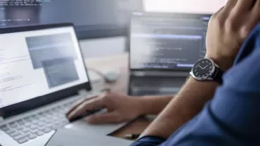 Personne utilisant un ordinateur portable avec du code à l'écran.