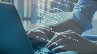 Une personne tape du code sur un ordinateur portable.