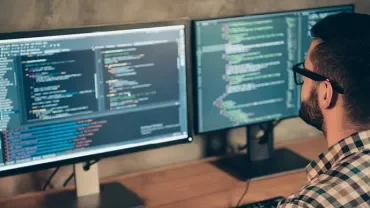 Personne travaillant sur deux écrans d'ordinateur avec du code.