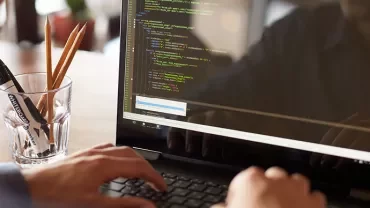 Personne tapant du code sur un ordinateur portable.
