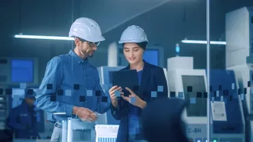 Personnes en casque examinant une tablette dans une usine.