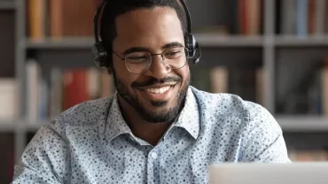 Personne souriante avec casque, utilisant un laptop.