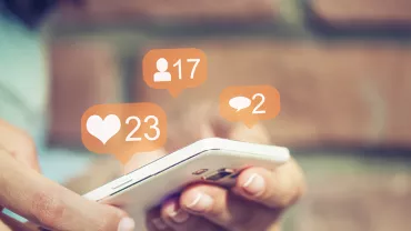 Personne tenant un téléphone avec des icônes de médias sociaux.
