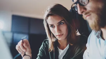 Deux personnes travaillant ensemble sur un projet à l'ordinateur.