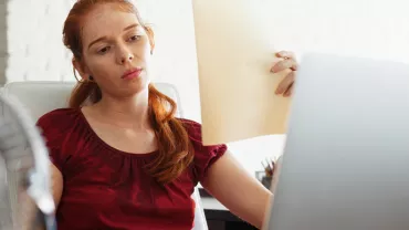 Personne regardant un document devant un ordinateur.