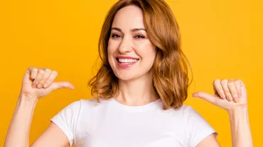 Personne souriante en t-shirt blanc sur fond jaune.