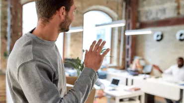 Personne se levant pour saluer des collègues dans un bureau moderne.