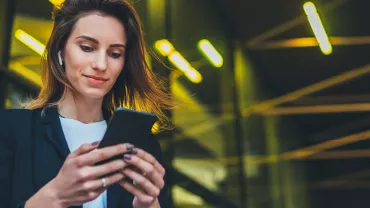 Personne utilisant un smartphone à l'extérieur, écouteurs sans fil.