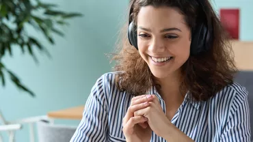 Personne souriante avec des écouteurs, travaillant en ligne.