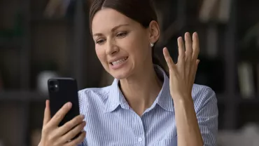Personne regardant un téléphone avec une expression de frustration.