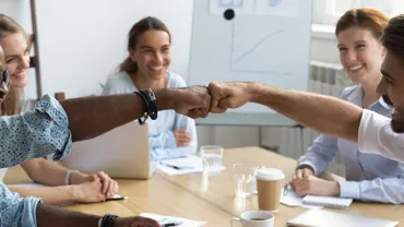 Groupe de collègues souriants faisant un check du poing.