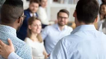 Groupe de personnes en réunion, deux individus au premier plan de dos.