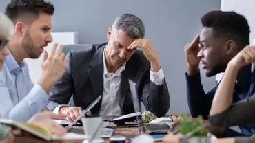Réunion de travail avec des personnes réfléchissant à une table.