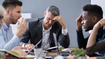 Réunion de travail avec des personnes réfléchissant à une table.