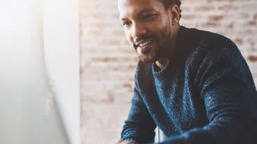 Personne souriante travaillant sur un ordinateur portable.