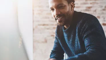 Personne souriante travaillant sur un ordinateur portable.