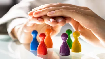 Mains couvrant des pions colorés sur une table.