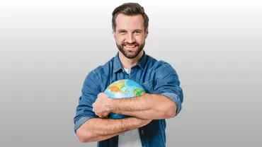 Personne tenant un globe terrestre avec un sourire.