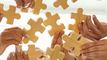 Des personnes tenant des pièces de puzzle en bois.