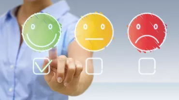 Une personne choisit un visage heureux parmi trois options d'humeur
