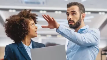 Deux personnes en discussion dans un bureau moderne.