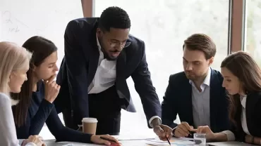 Groupe de personnes en réunion autour d'une table avec des documents.