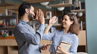 Deux personnes se tapant dans la main dans un bureau moderne.