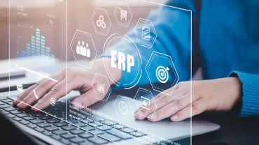 Personne utilisant un ordinateur avec des graphiques ERP à l'écran.