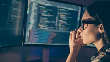 Personne travaillant sur des écrans avec du code informatique.