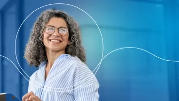 Personne souriante avec des lunettes à l'intérieur.