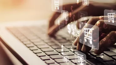Mains tapant sur un clavier avec des icônes de panier d'achat.