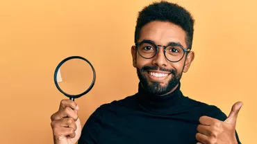 Personne souriante avec loupe et pouce levé.