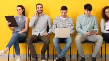 Groupe de personnes assises contre un mur jaune.
