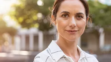Personne souriante en chemise rayée dans un parc.