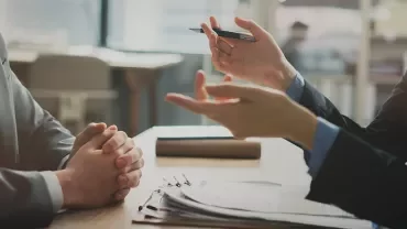 Personne consultant une fiche de paie ou utilisant une calculatrice à son bureau. 