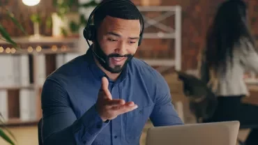 Homme souriant au téléphone devant son ordinateur
