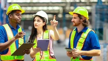 Chef d'équipe avec tablette dans un entrepôt, entouré de collègues