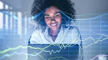 Femme souriant devant un ordinateur qui projette des courbes et graphiques