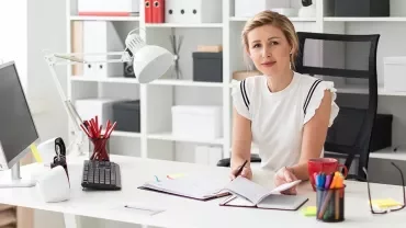 Femme devant son bureau de travail avec ordinateur et classeur devant elle