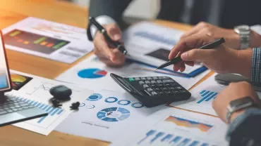 Analyste financier ou cadre finance devant des graphiques financiers sur écran. 