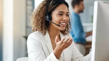 Conseiller(ère) client avec casque audio souriant(e) dans un centre de contact moderne. 