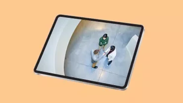 Tablette représentant trois personnes vues d'en haut, au bureau, en train de discuter de travail.